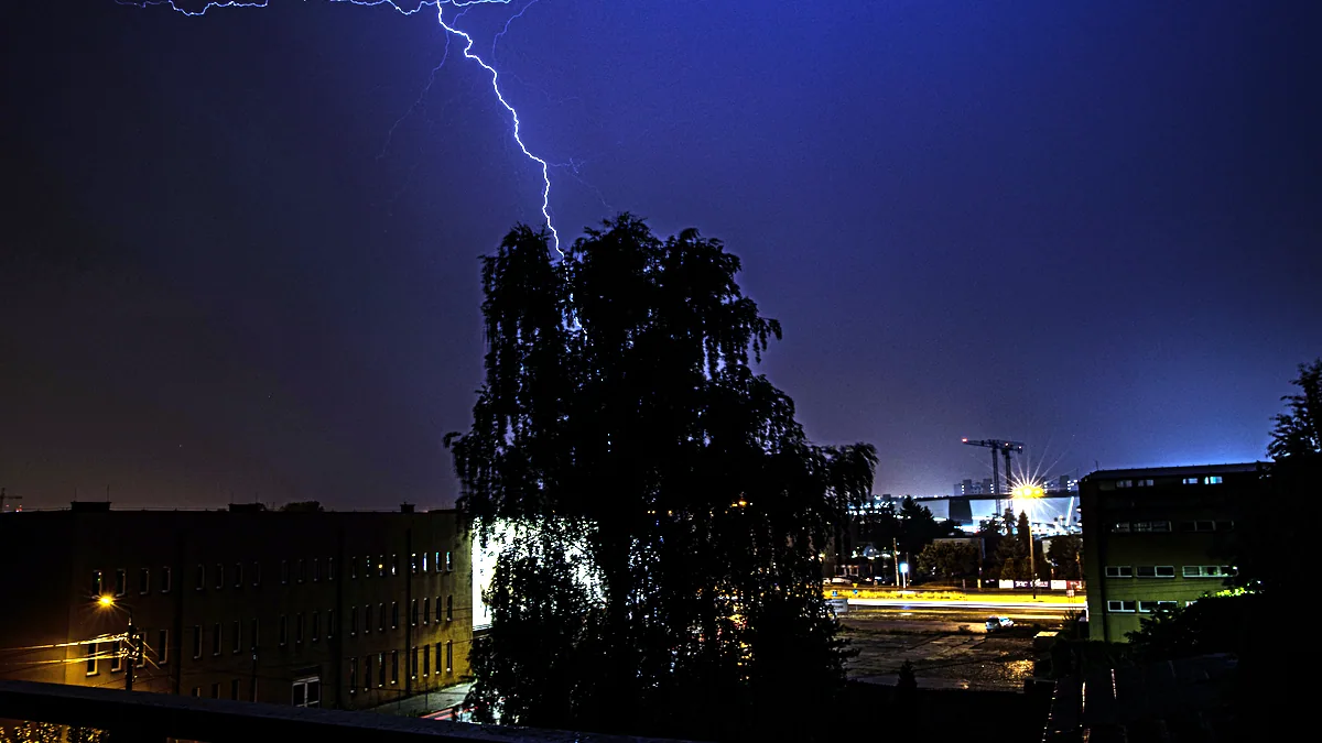 A sudden flash of lightning splitting a dark summer sky over the city.