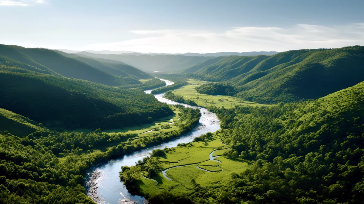 A slow river bending through green hills in soft afternoon light.