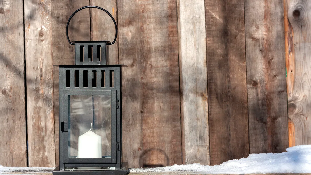 A single candle flickering on the sill of a creaking wooden door.