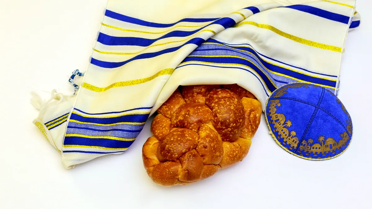 A braided loaf of challah on a white lace tablecloth at a family table.