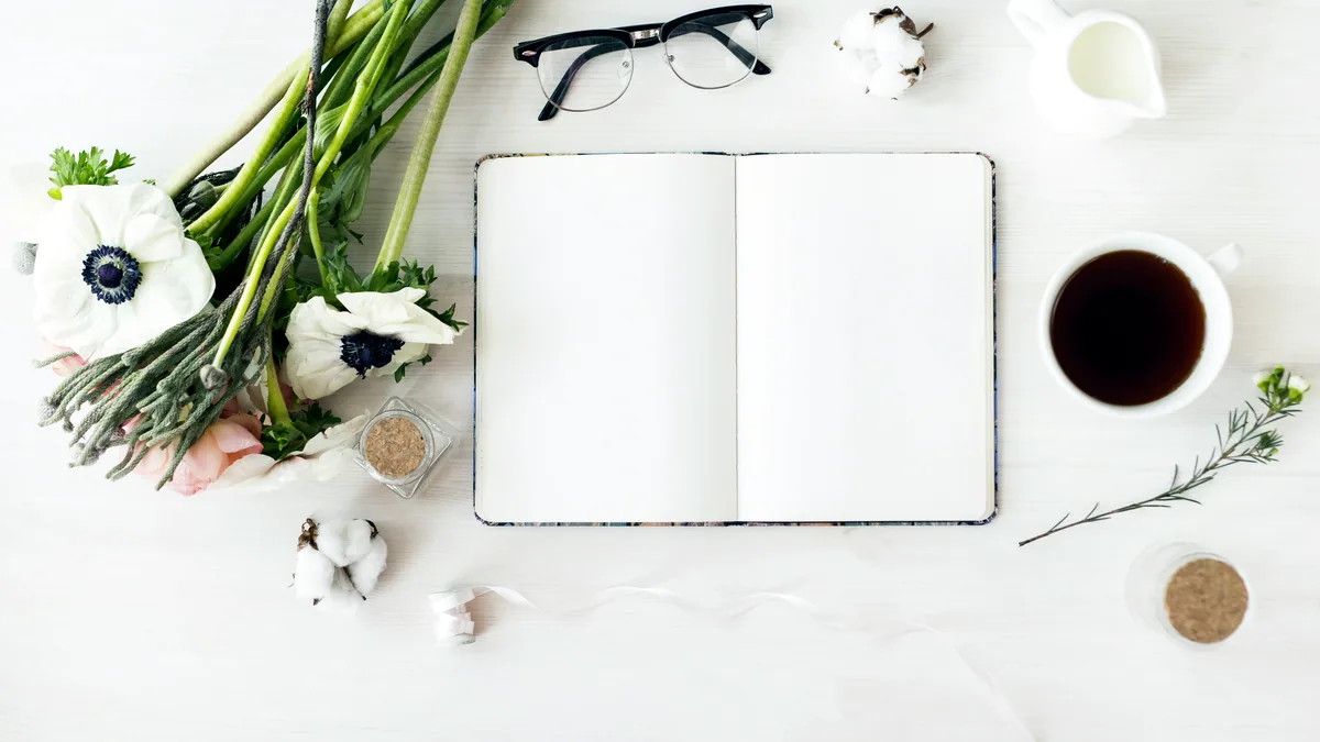 An open poetry magazine with fanned pages resting on a cool white desk.